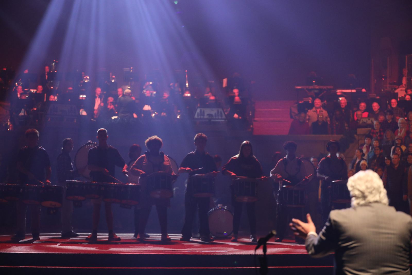 Conductor leading the orchestra and drumline