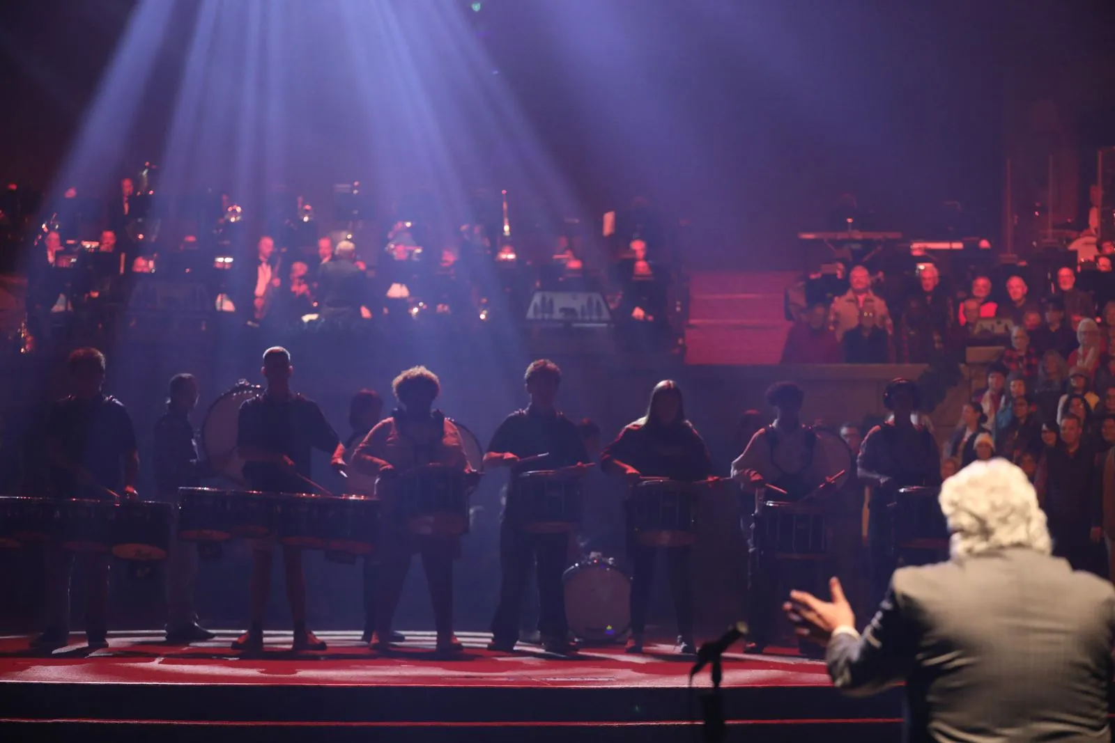Conductor leading the orchestra and drumline