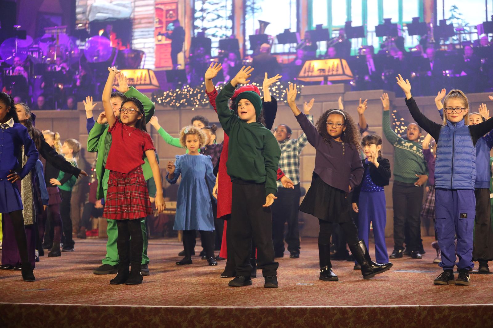 Kids worship choir with arms raised on stage