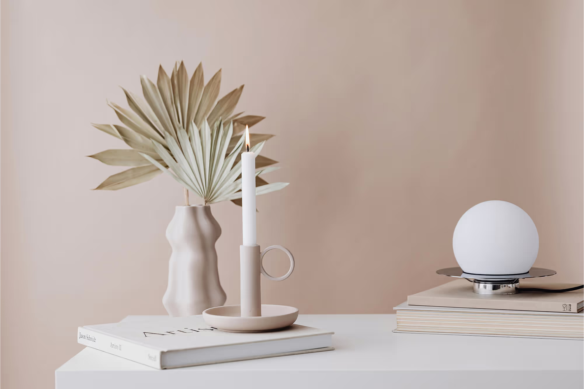 A table with a vase and a candle on it.