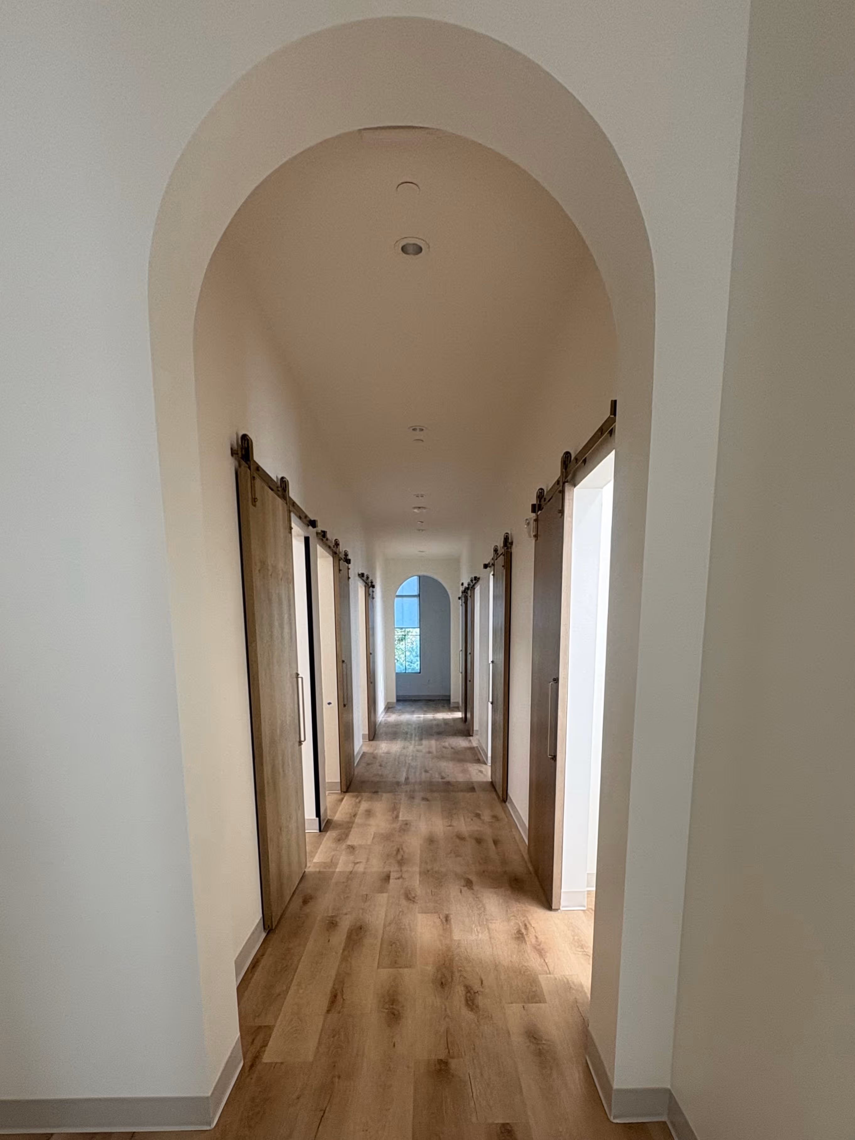 A long hallway with wooden doors leading to another room.
