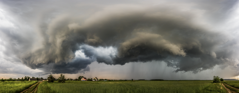 A large cloud gathers over a farm in the distance