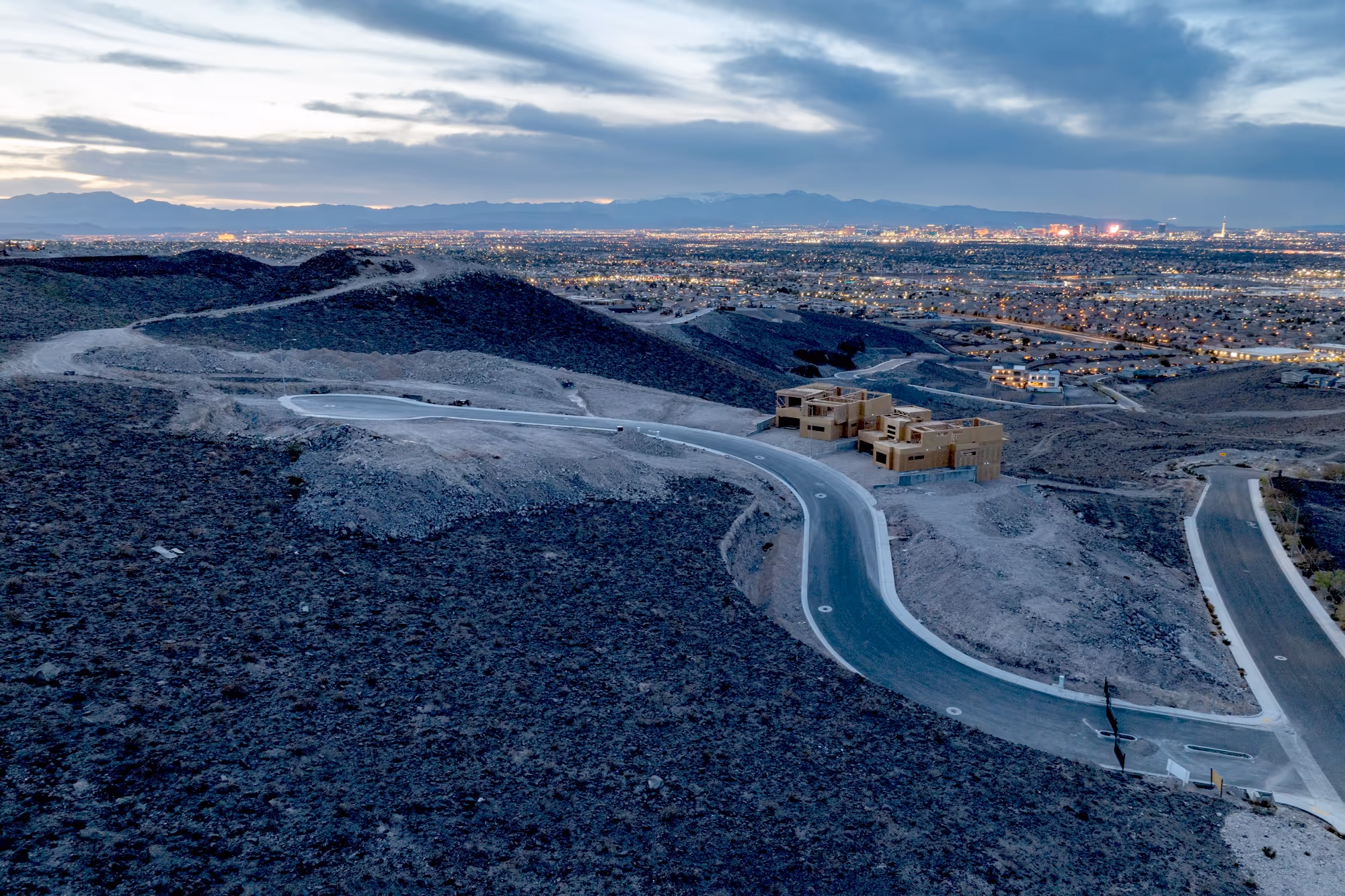 A full view of the Alta Vista development lot at dusk with Las Vegas lights in the distance