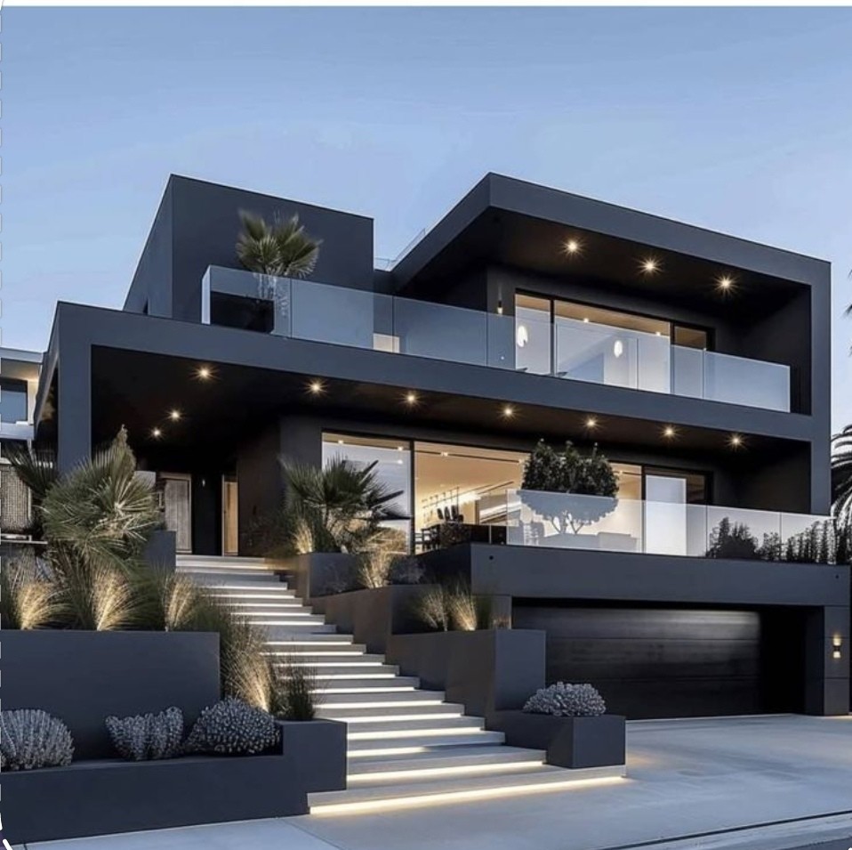 Modern three-story house with dark exterior, illuminated stairs, glass balconies, and landscaped plants.