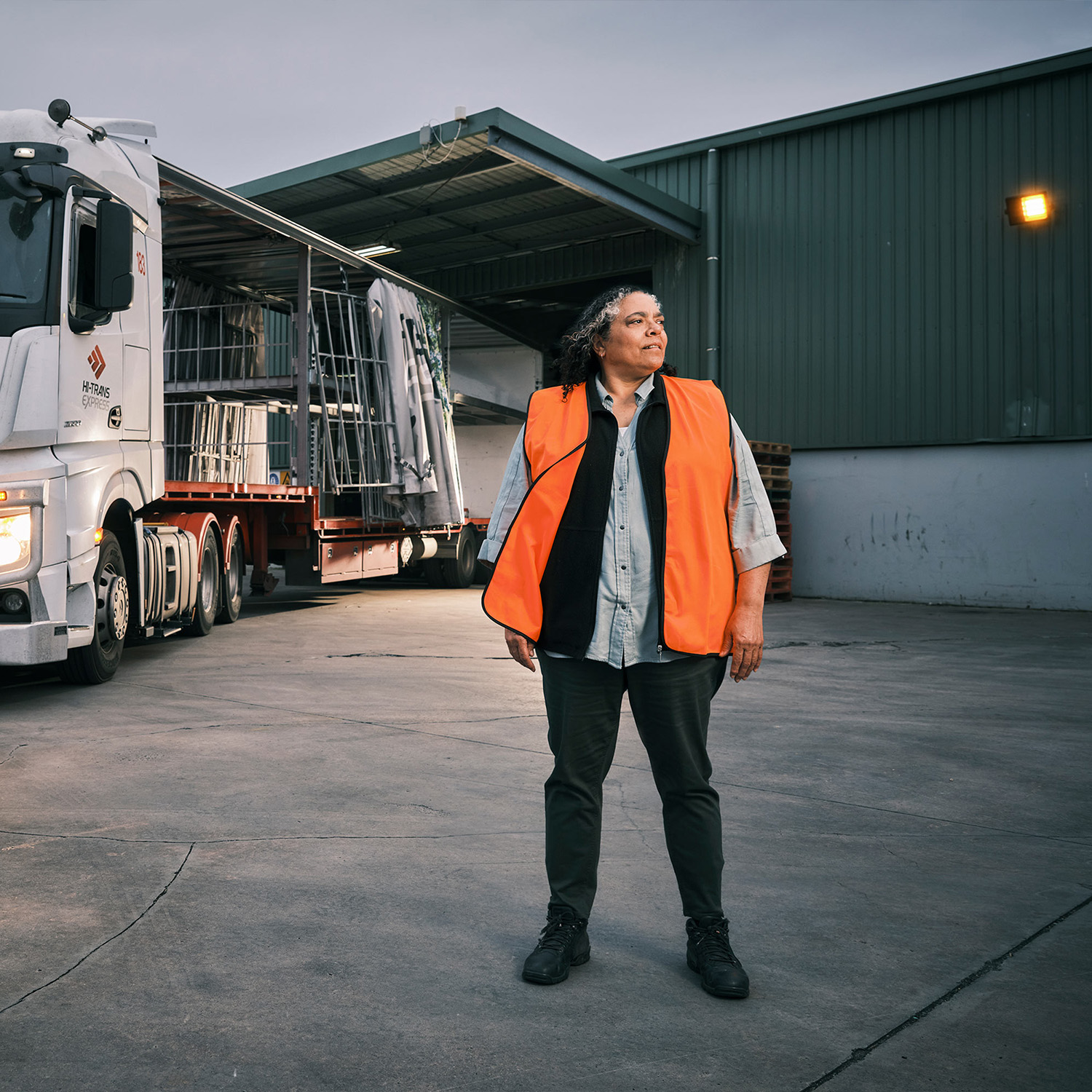 Woman in hi-vis standing outside depot
