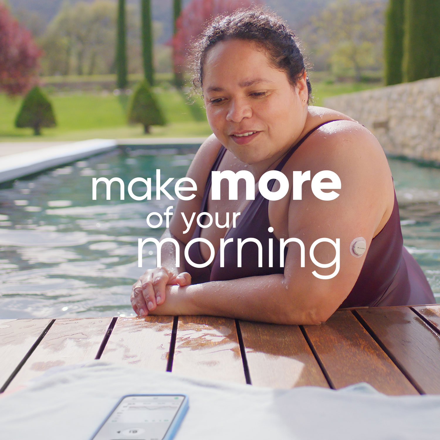 Woman wearing Dexcom sensor in pool checks readings on smartphone app