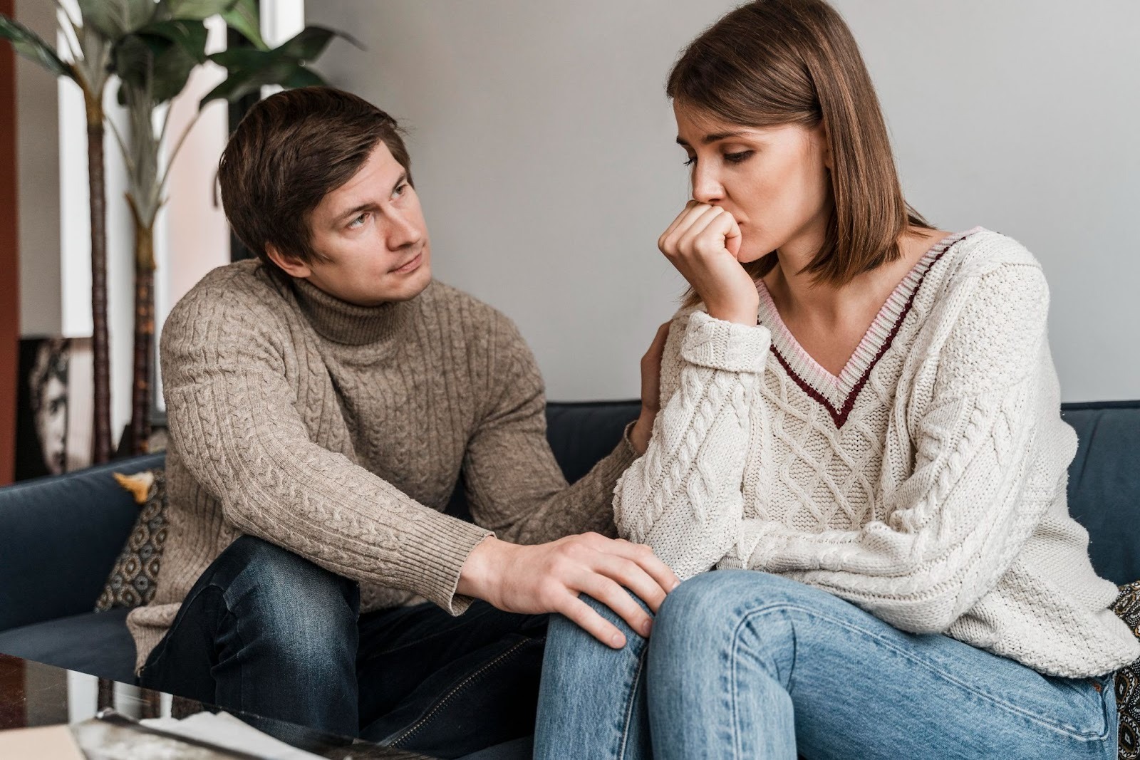 A couple sitting in a couch where the man comforts his anxious wife