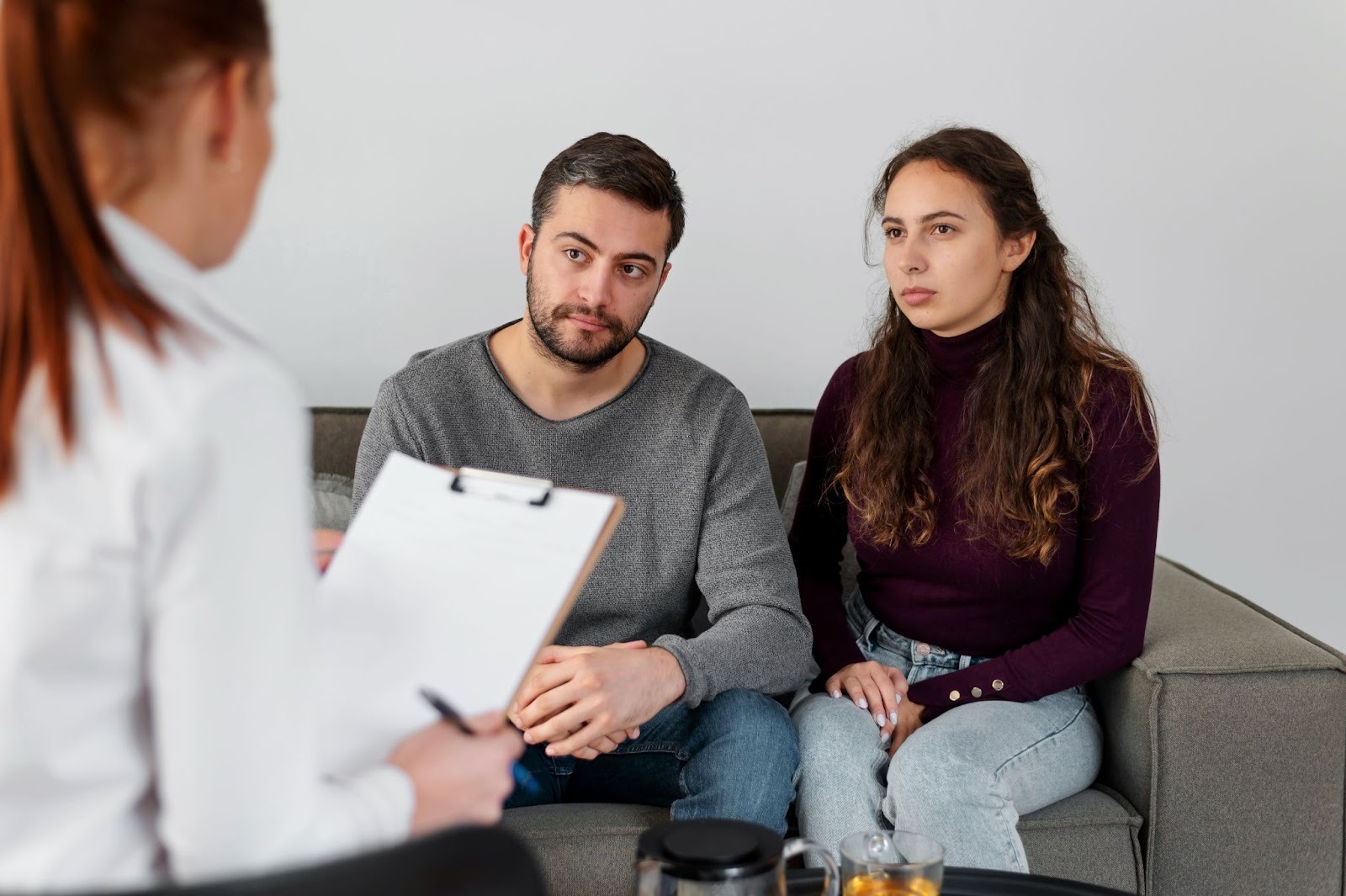 A couple sitting on a couch and attending a therapy session with a counselor
