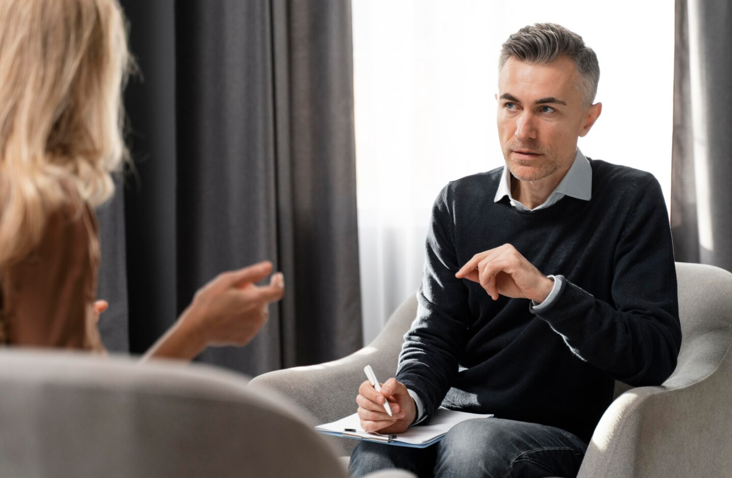 A man and woman sitting in chairs, actively discussing how to combat fatigue after quitting alcohol