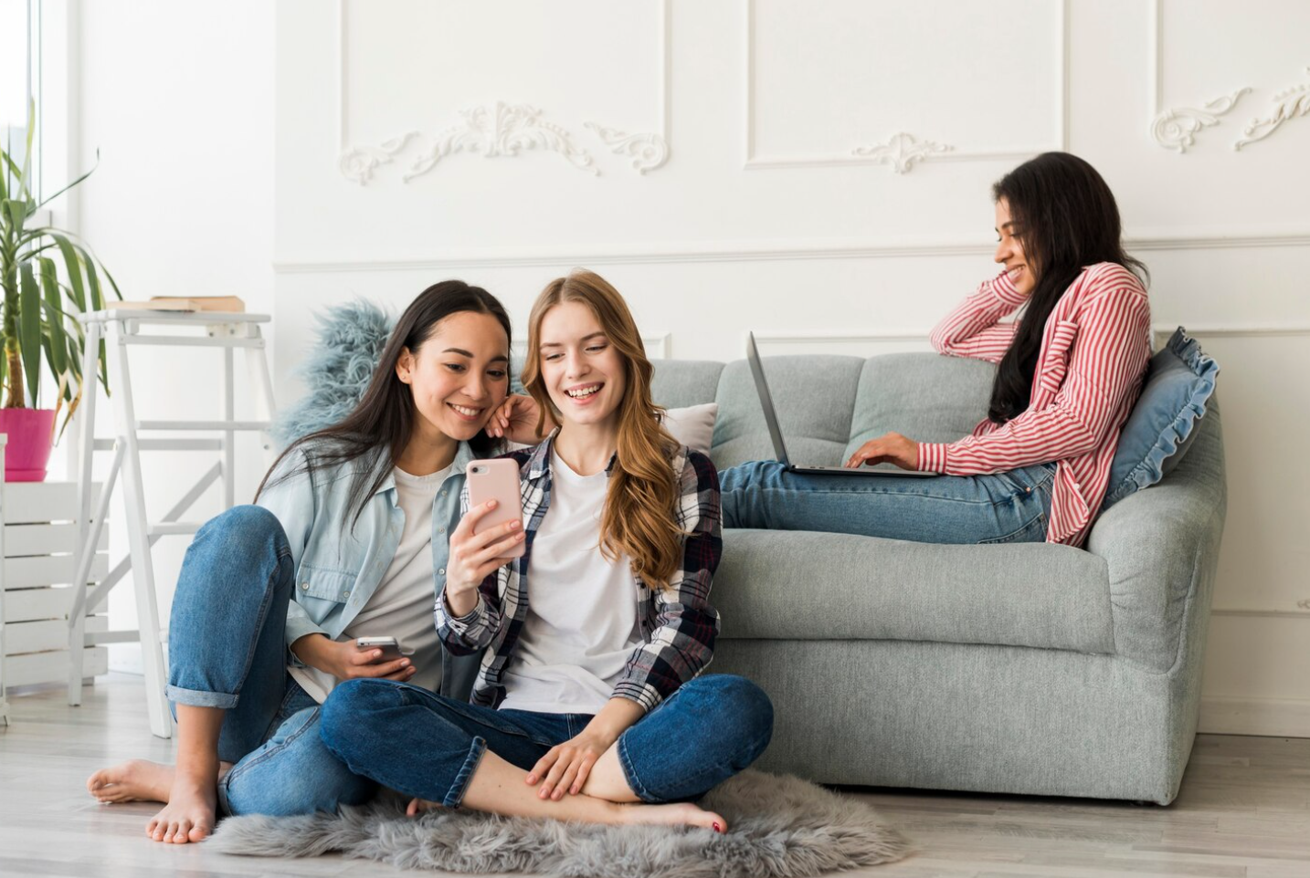 Three women sitting together in a comfortable living room, illustrating peer support and community life within a sober living home