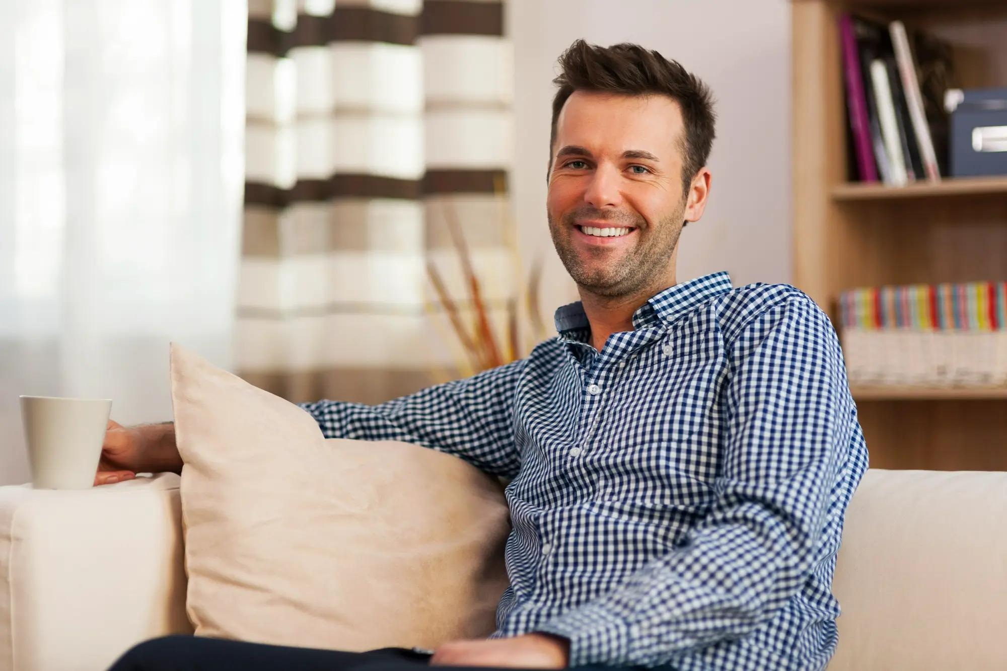 Man relaxing on a couch in a comfortable sober living home, representing stability, recovery, and rebuilding daily life after addiction treatment.