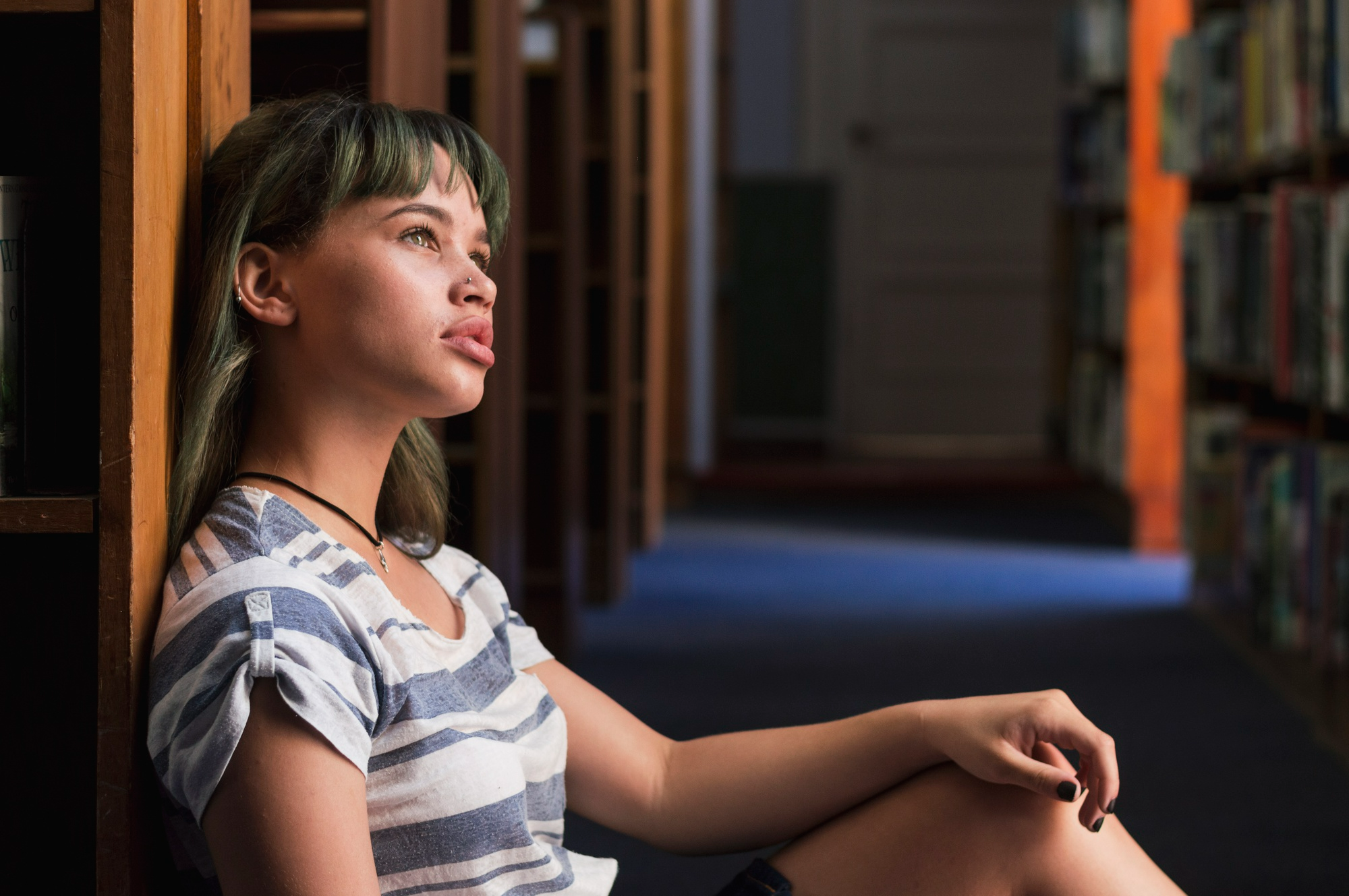 Woman sitting in a peaceful indoor setting, illustrating the personal decision between inpatient and outpatient addiction treatment.