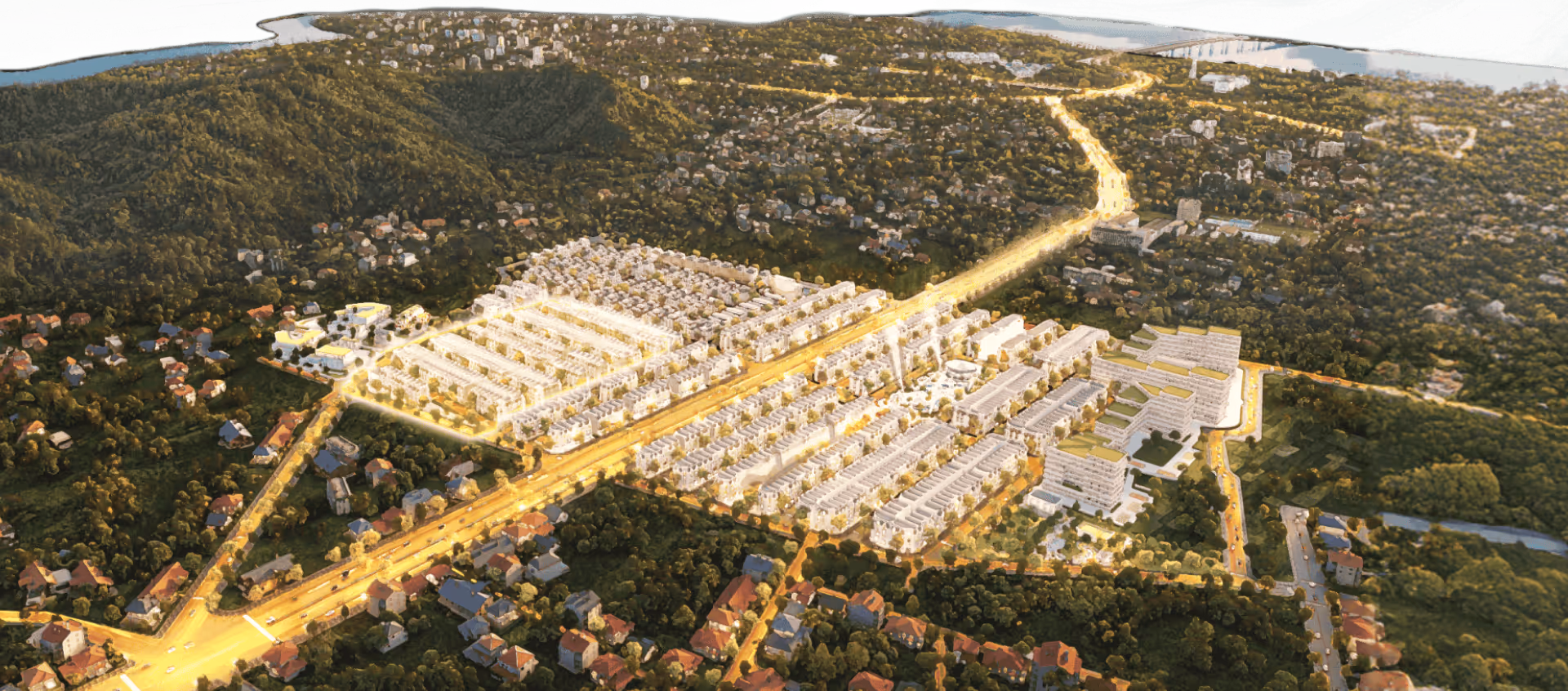 Aerial view of a residential area with illuminated streets, surrounded by dense greenery and hills, with a river and bridge in the distance.