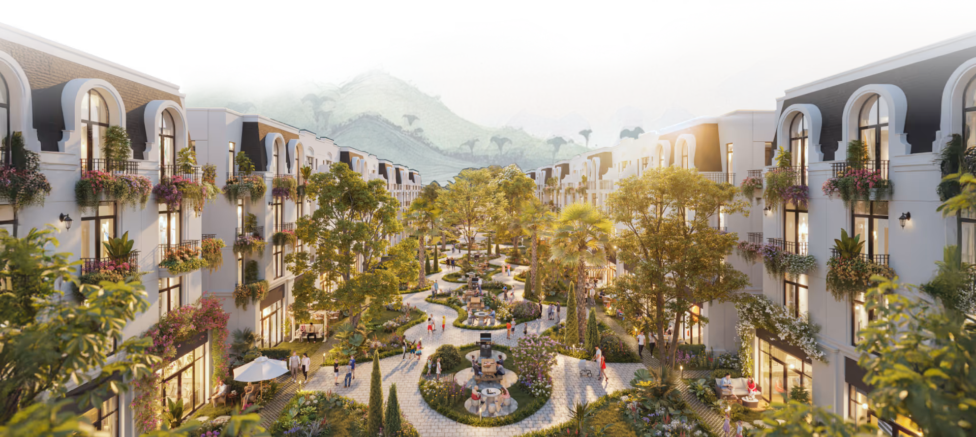 A landscaped pedestrian promenade with trees, greenery, and people walking between rows of modern white buildings with balconies adorned with flowers.