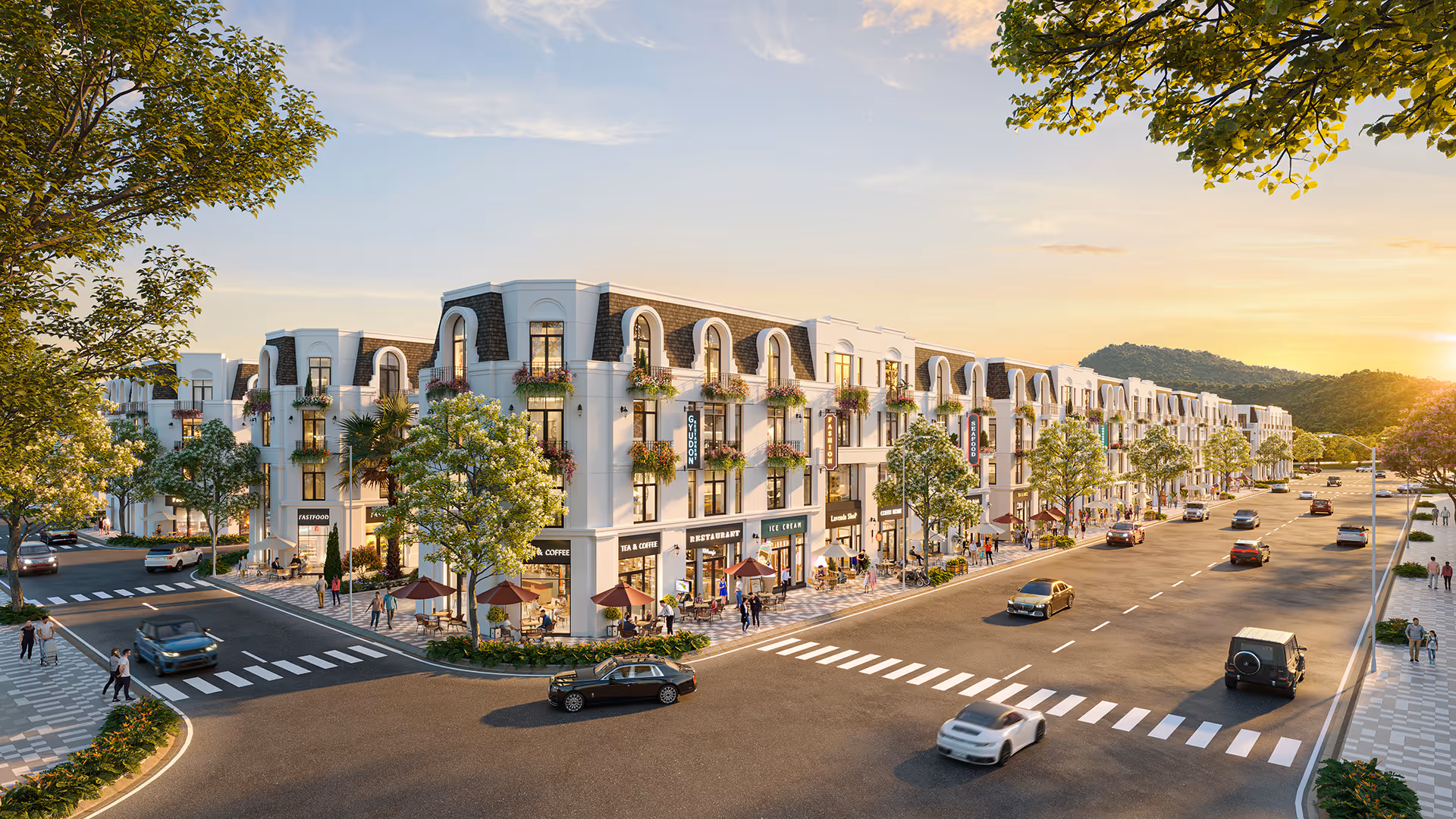 Sunlit modern European-style street with white buildings featuring shops, outdoor seating, trees, and cars on the road.