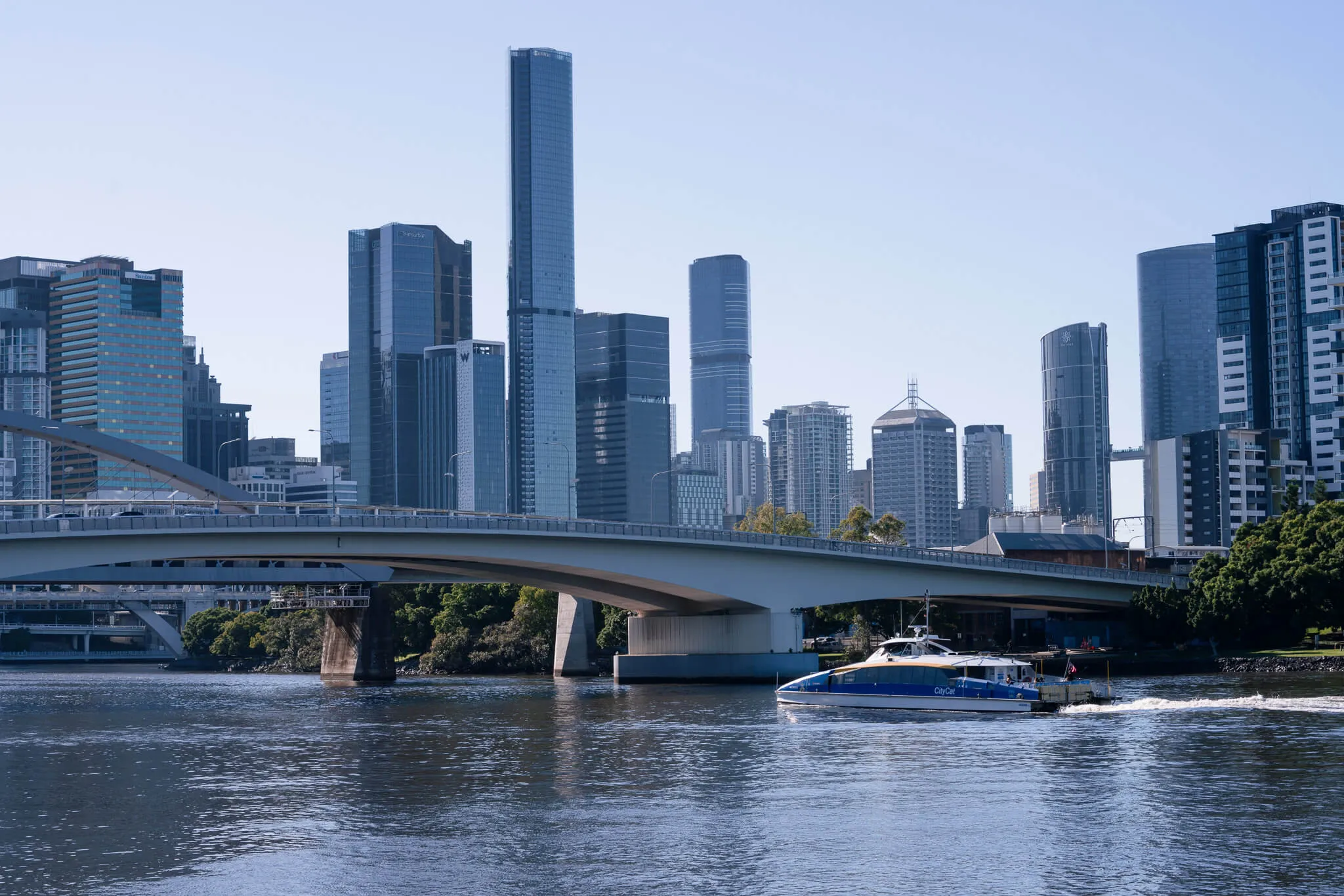 Passenger ferry crossing river with modern city skyline in background