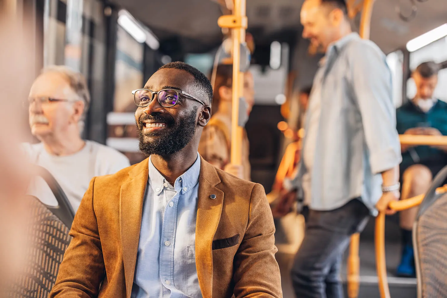 Smiling passenger seated on a bus surrounded by other commuters