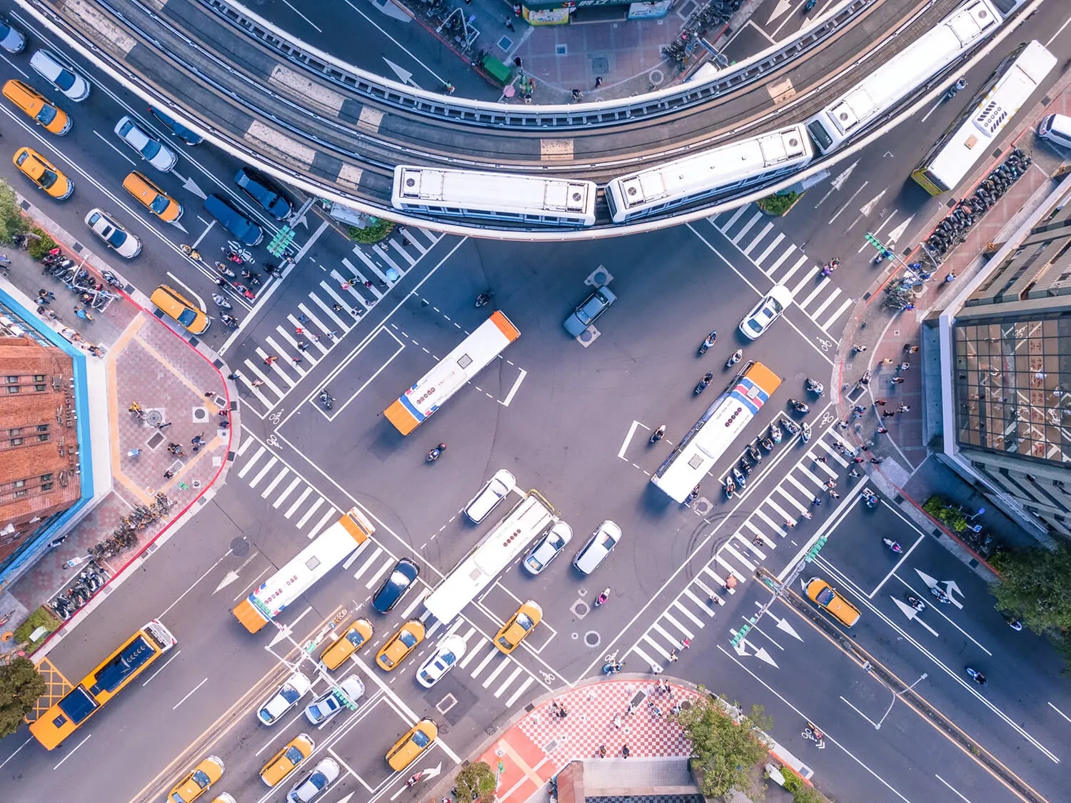 Aerial view of busy city intersection with buses, cars, and trains in motion