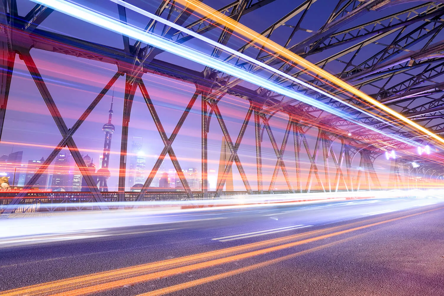 Light trails of vehicles crossing steel bridge at dusk representing connected transport