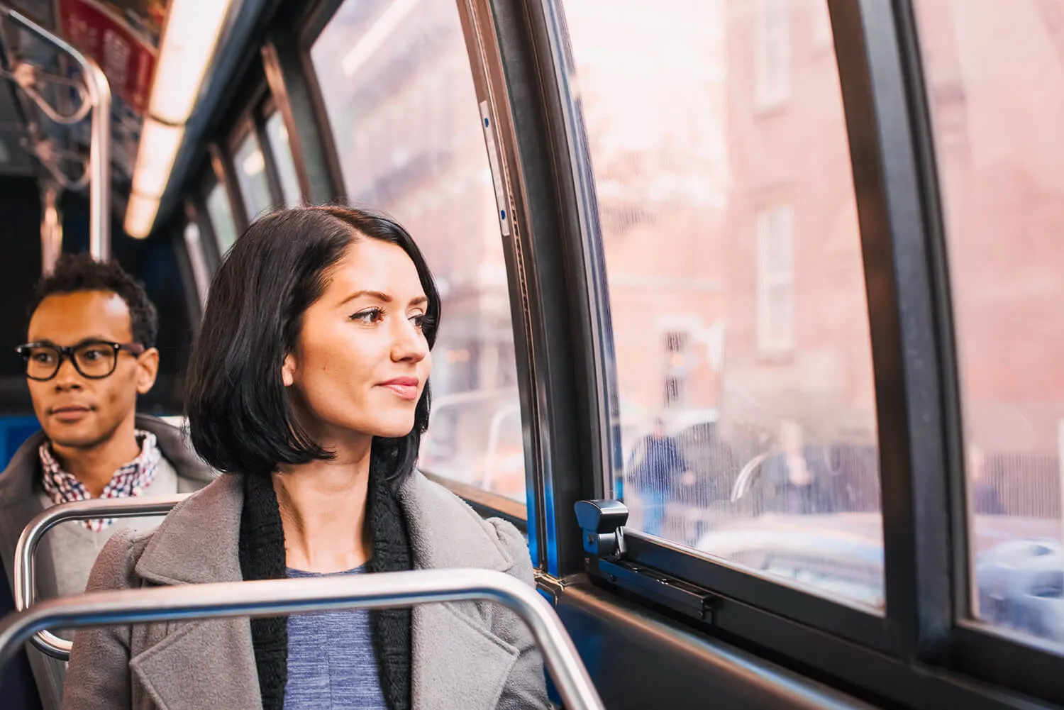 Commuters seated on city bus looking out the window during transit