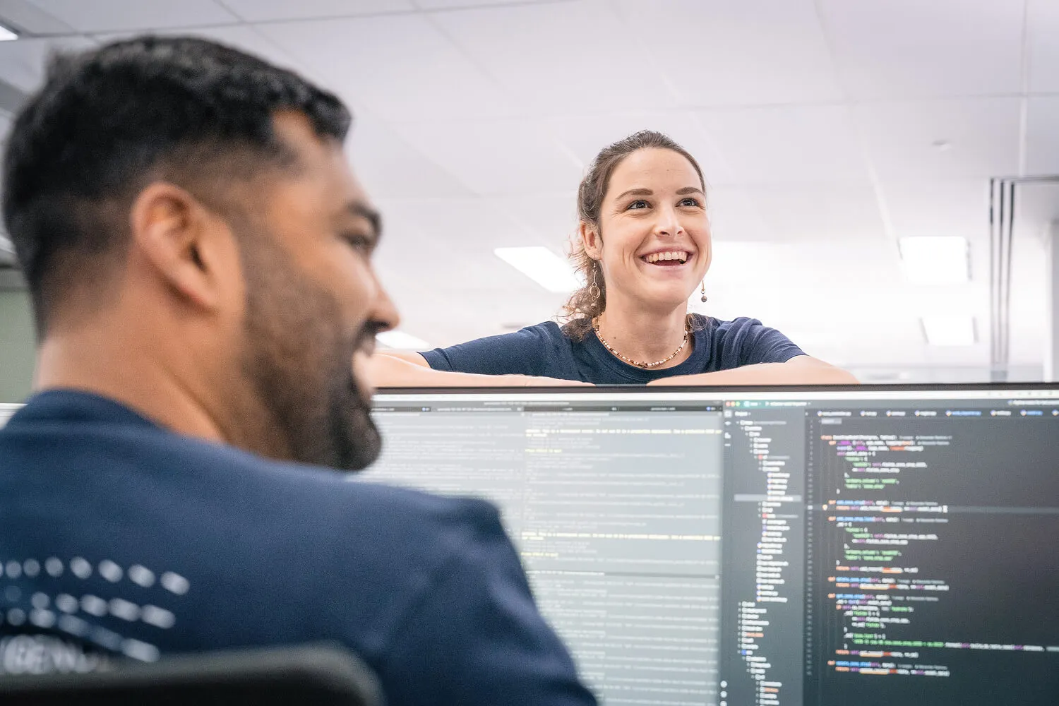 Intermoda developers collaborating while reviewing code on dual monitors