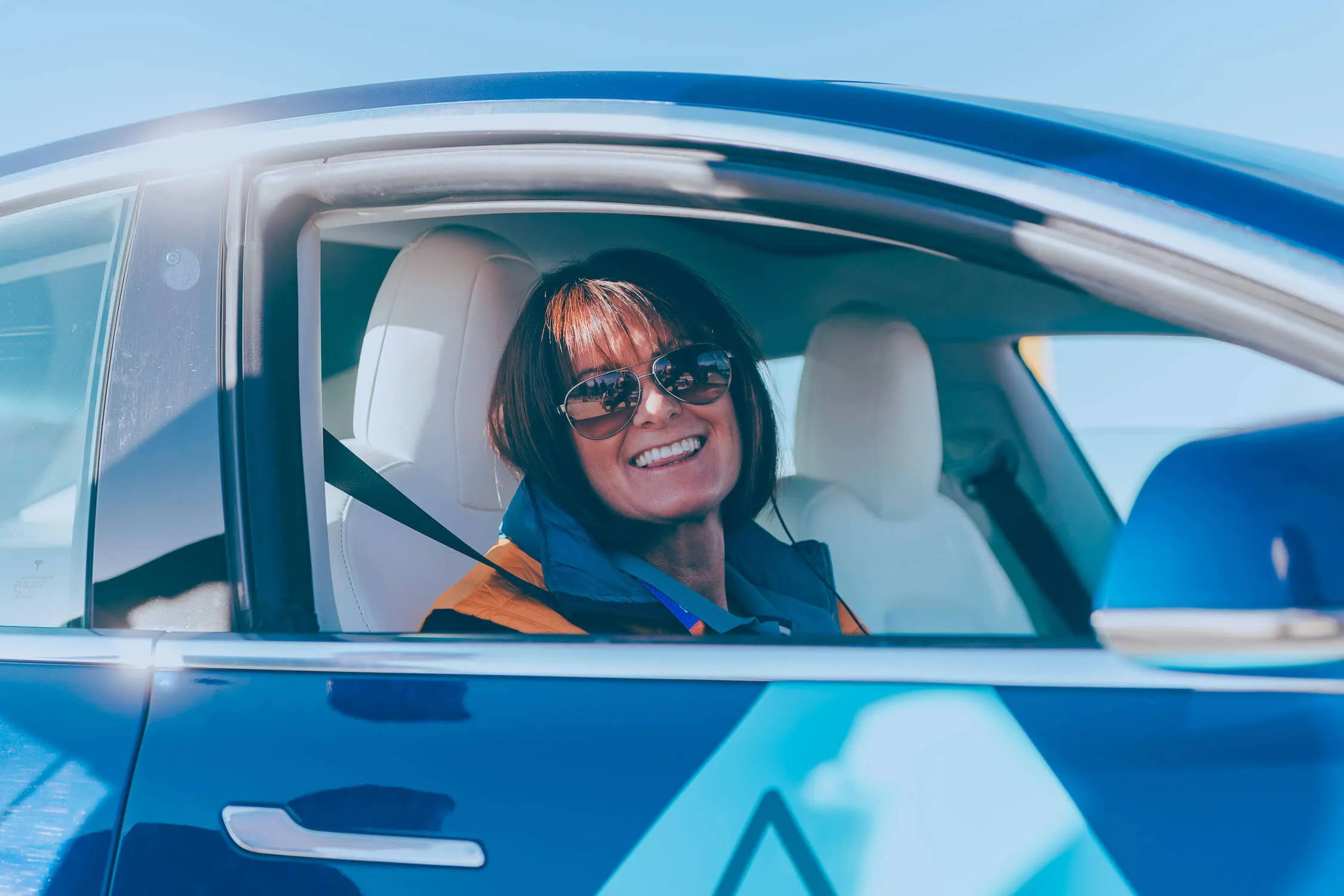 Smiling driver sitting inside a branded vehicle, wearing uniform and sunglasses