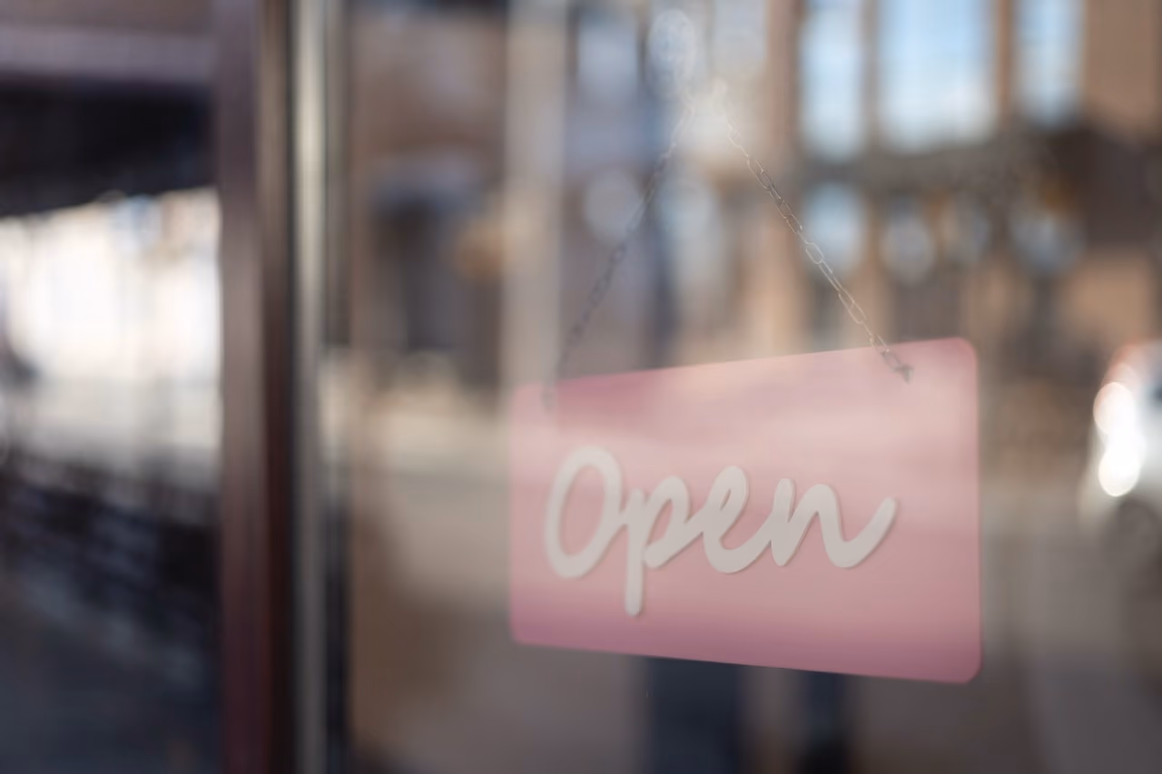 Open pink sign hanging on window, storefront or shop promotion