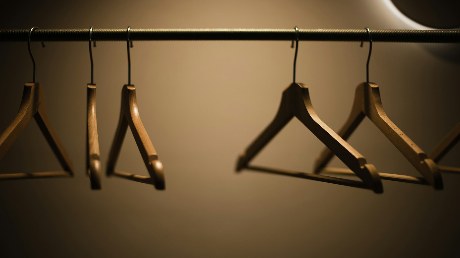 Cintre seul suspendu à une tringle en métal noir, composition minimaliste en noir et gris, sans vêtement