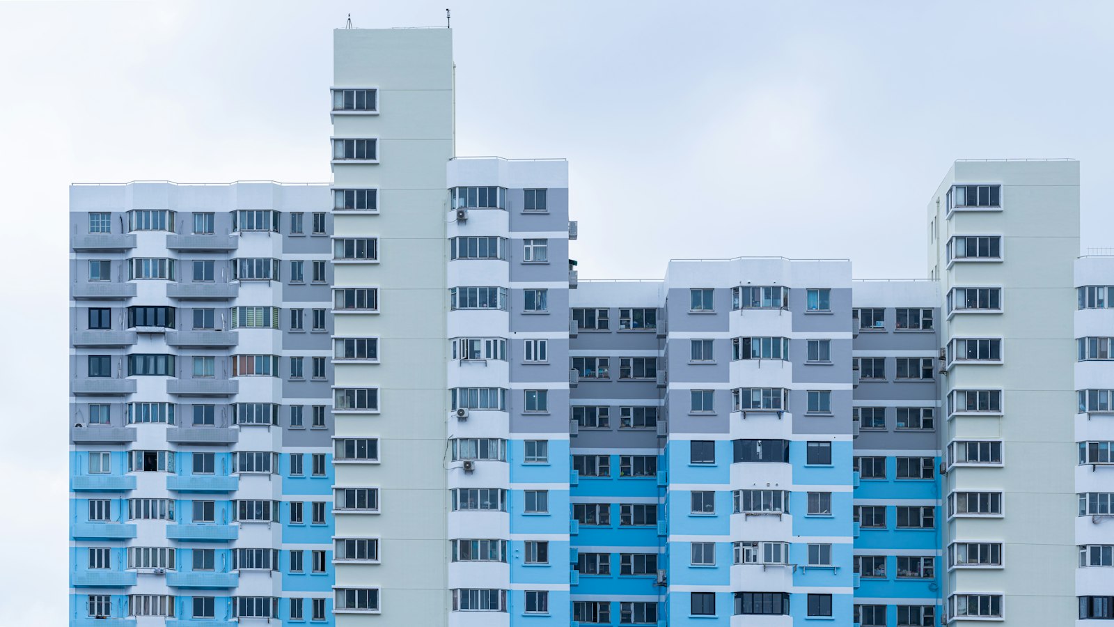 Façades bleues et blanches d’immeubles d’habitation modernes, fenêtres et balcons alignés en motif géométrique