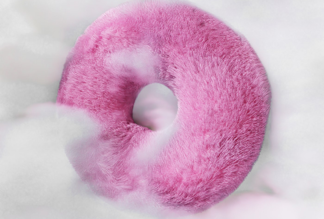 A pink donut sitting on top of a white surface.