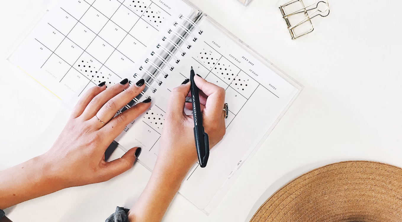 A person writing on a notebook with a pen.