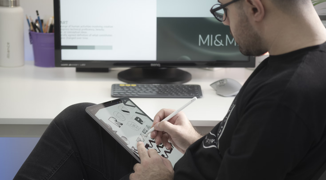 A man sitting in front of a computer holding a pen.