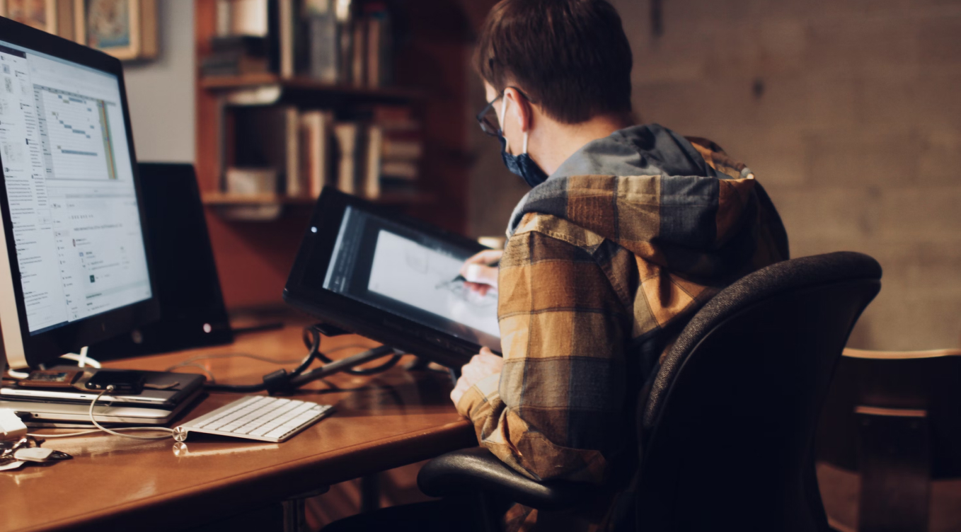A young man sitting at a desk using a computer.