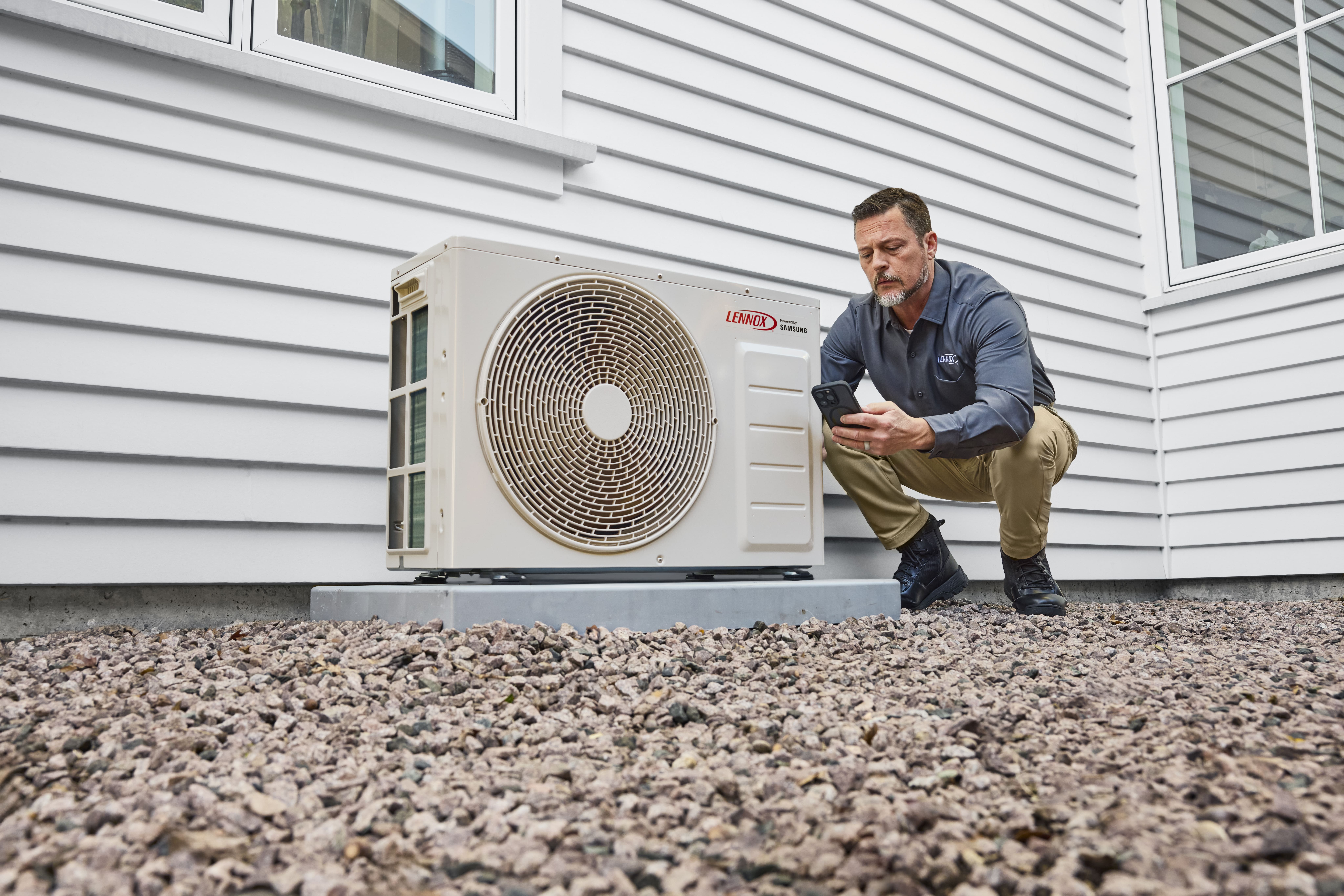 Technician repairing air conditioning unit outside building