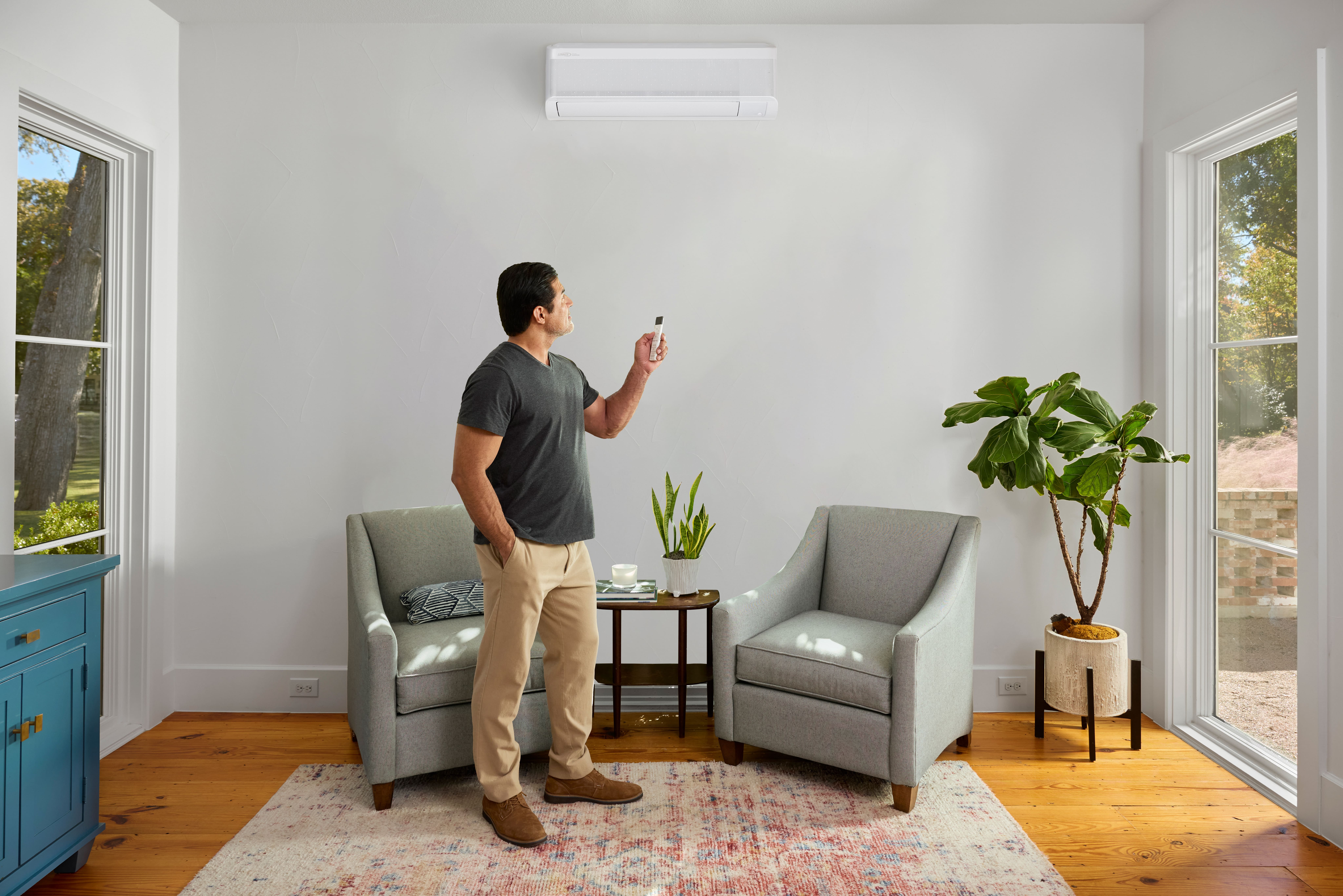 Man turning on an air conditioning unit on a white wall