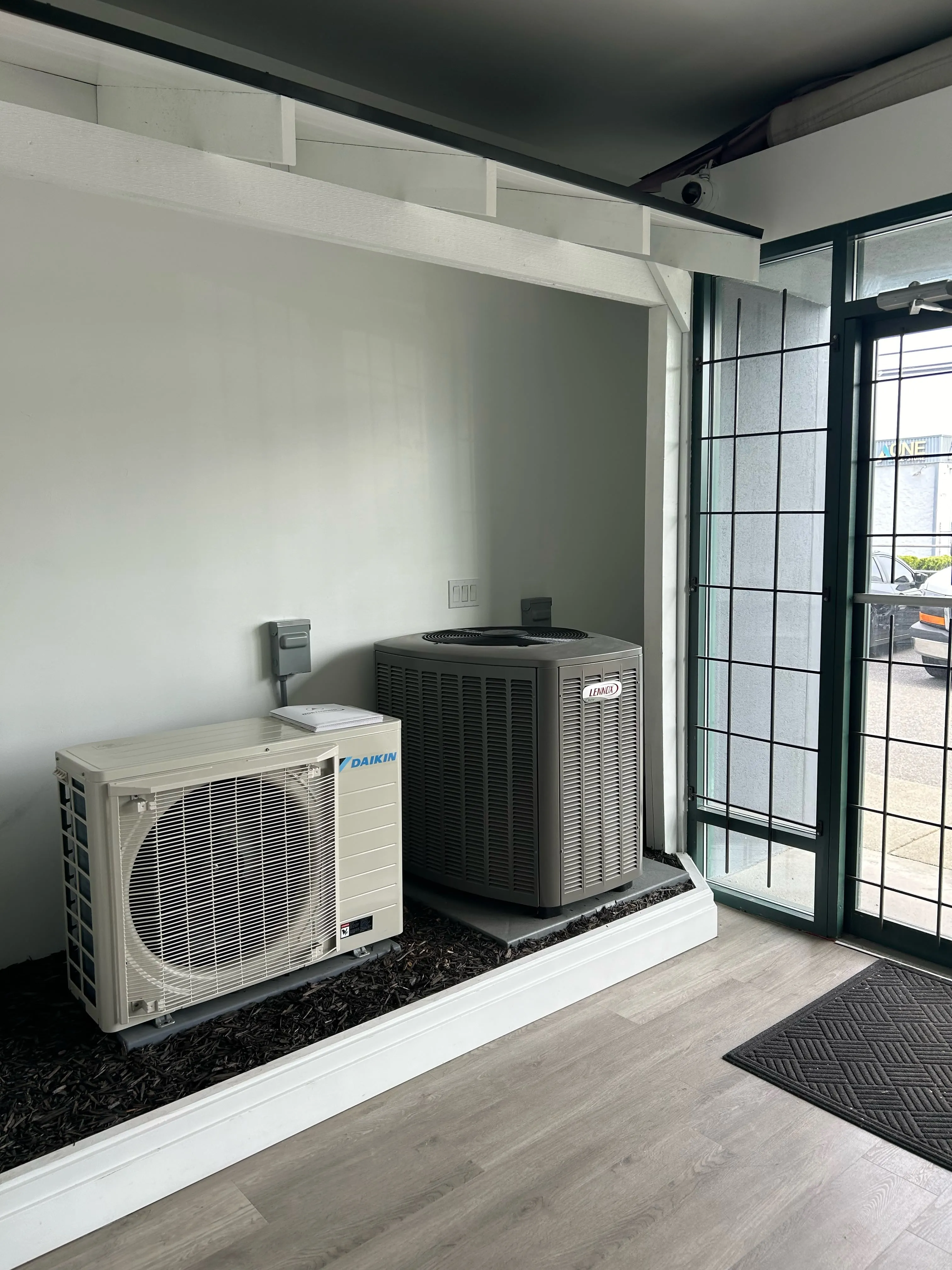 Daikin and Lennox HVAC units near window on raised platform