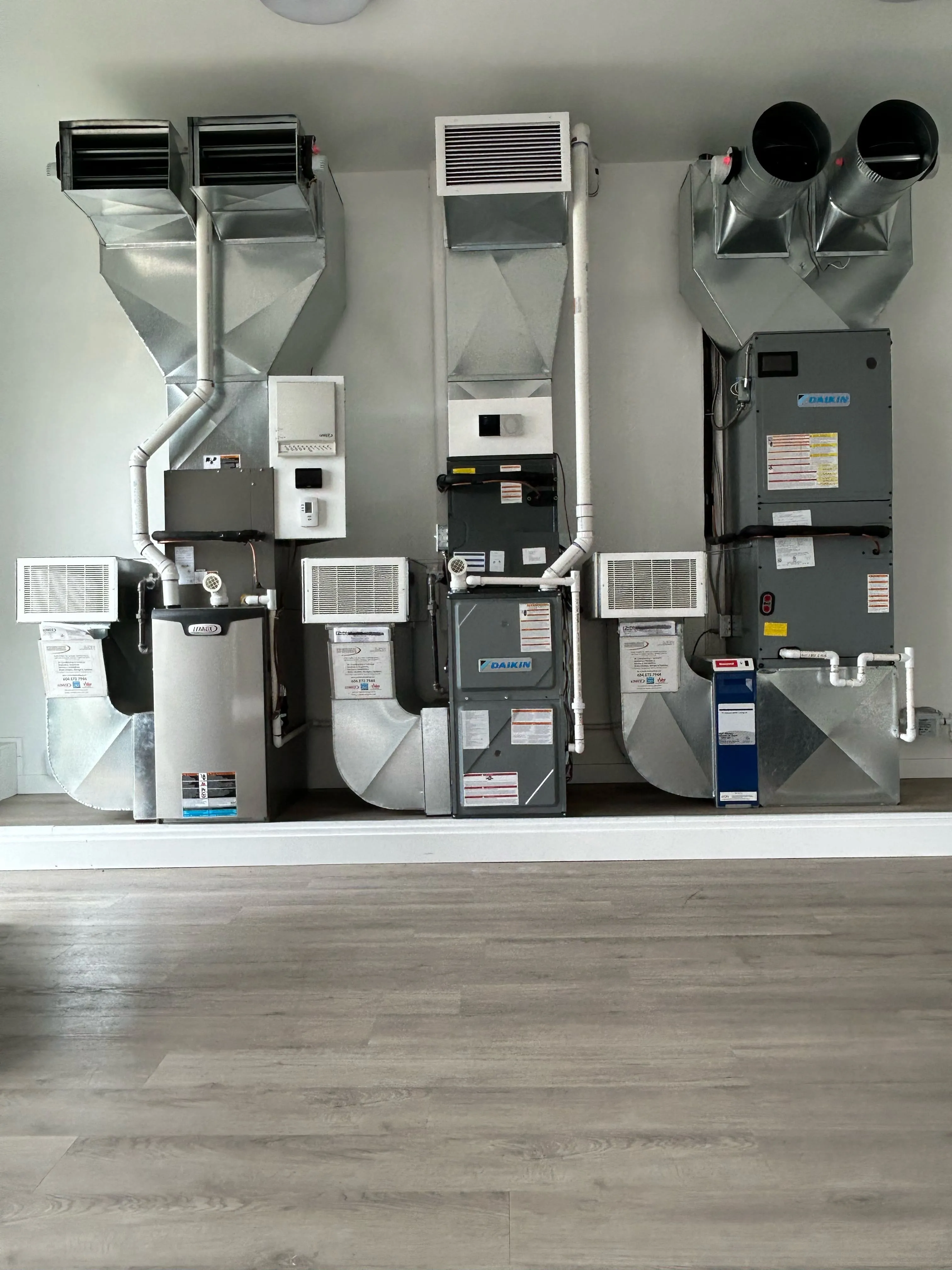 Three Daikin HVAC units mounted on a white wall with ventilation ducts
