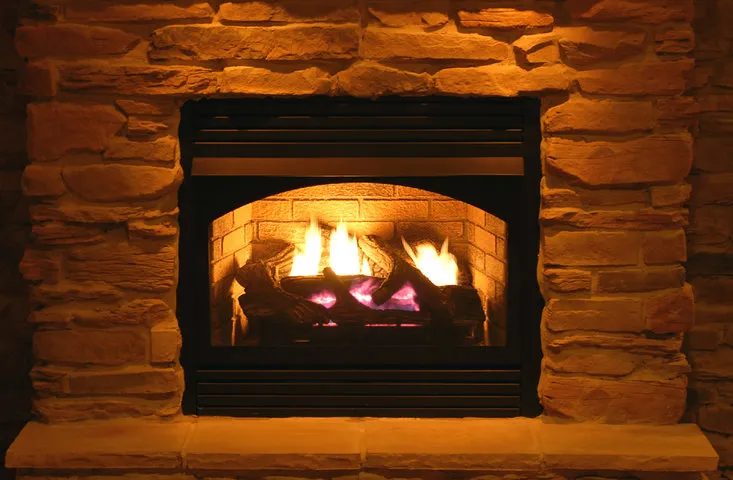 Warm stone fireplace with bright flames burning in a cozy setting