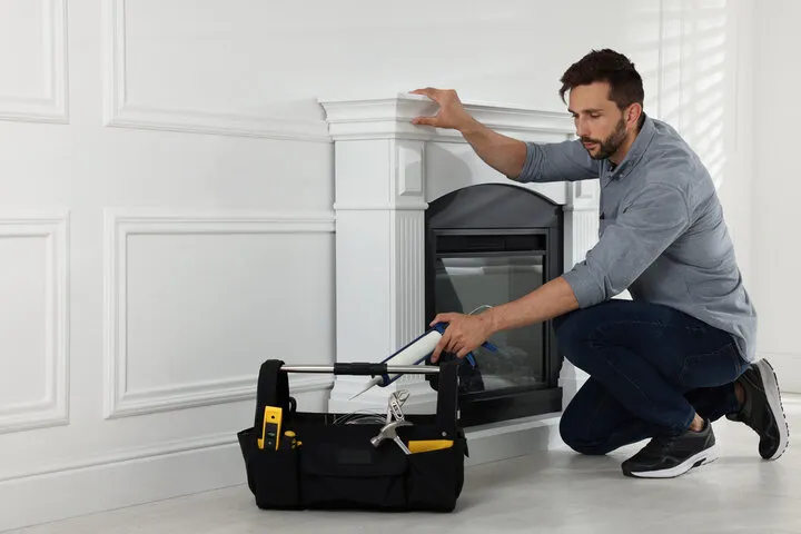 Worker installing or repairing fireplace mantel with tools nearby
