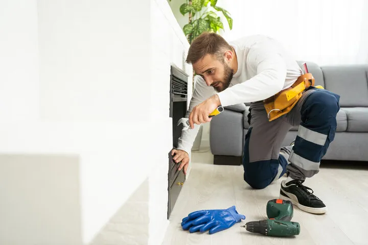Worker repairing appliance, using tools near blue gloves and drill