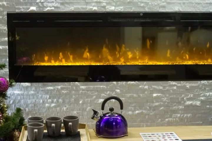 Modern electric fireplace with yellow flames, purple kettle, and gray mugs