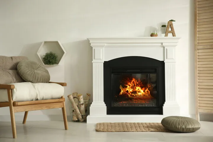 Cozy living room with white fireplace, burning fire, and modern chair