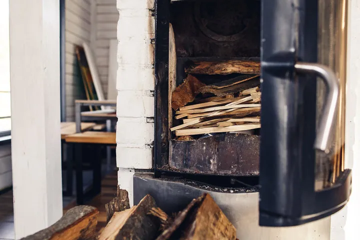 Rustic wood stove with firewood stacked inside and beside it