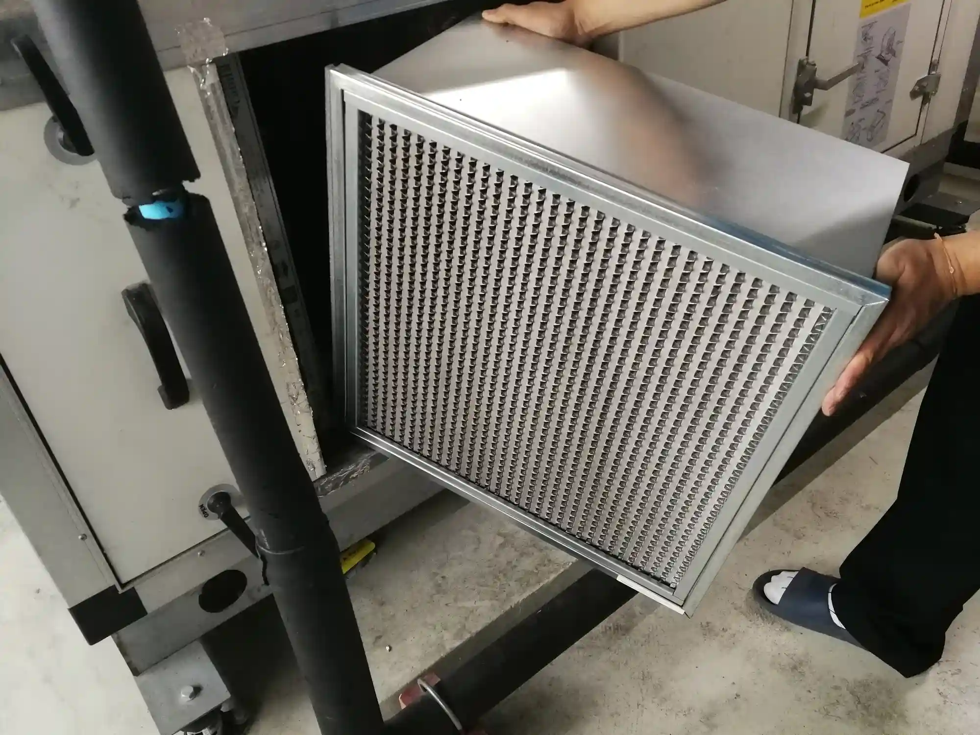 Metal air filter with dense grid pattern being handled in industrial setting