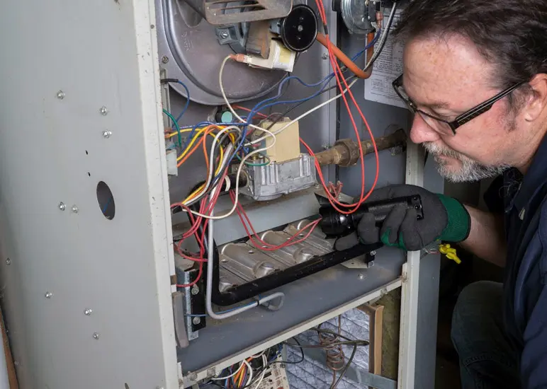 Technician inspecting electrical wiring inside an open industrial equipment panel