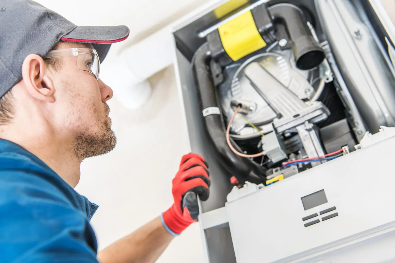 Technician in safety gear inspecting electrical panel with red gloves