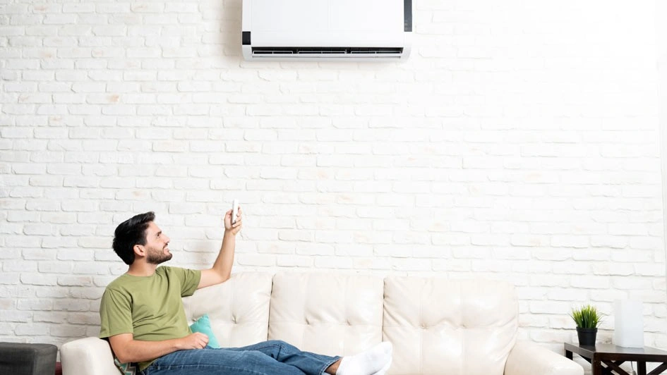 Person relaxing on couch, adjusting air conditioner remote control