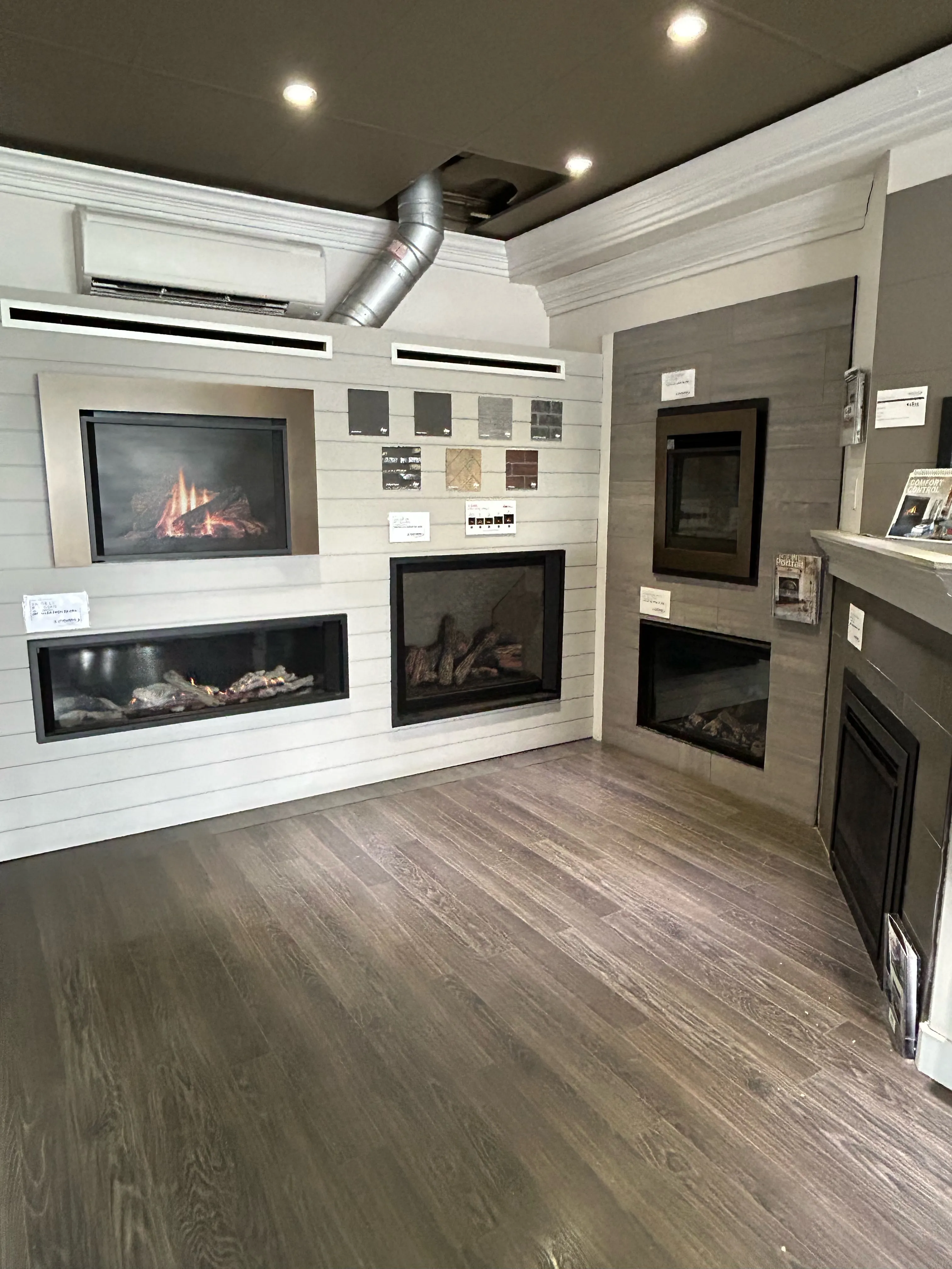 Showroom display of multiple modern gas fireplaces with wood floors