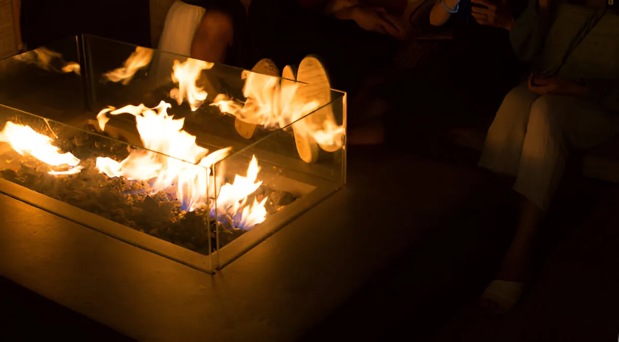 Modern glass fire pit burning brightly with orange and blue flames