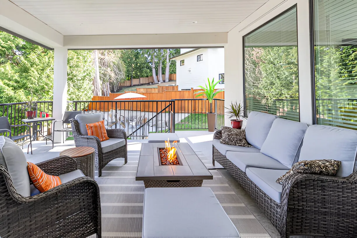 Cozy covered patio with wicker furniture and lit fire pit